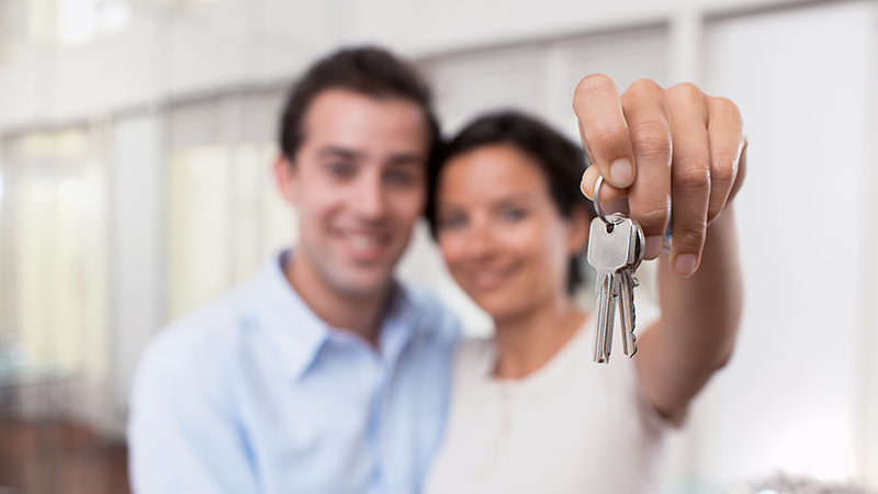 Happy couple holding the keys to their new house after thorough home inspection services 